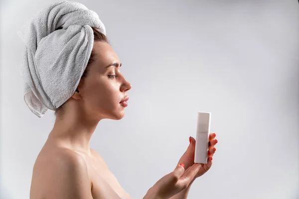 Красивая брюнетка девушка в белом полотенце держит косметику — стоковое фото