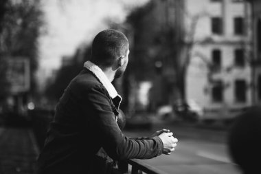 Kısa saçlı bir adam düşünceli ve yolun kenarında duruyor. Mesafeye bak. beklenti