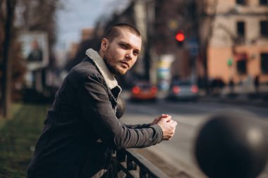 Kısa saçlı bir adam düşünceli ve yolun kenarında duruyor. Mesafeye bak. beklenti