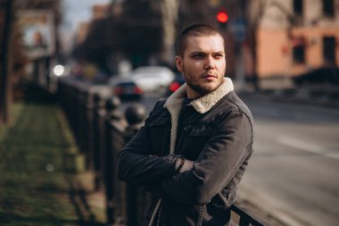 Kısa saçlı bir adam düşünceli ve yolun kenarında duruyor. Mesafeye bak. beklenti