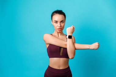 Güzel, sportif esmer kadın spor egzersizleri yapıyor mavi arka planda elleri var. Spor egzersizleri. izole.