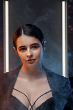 Stüdyoda siyah ceketli, profesyonel makyajlı güzel bir esmer kadının yakın plan portresi. çok renkli ışık.