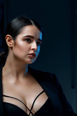 Stüdyoda siyah ceketli, profesyonel makyajlı güzel bir esmer kadının yakın plan portresi. çok renkli ışık.