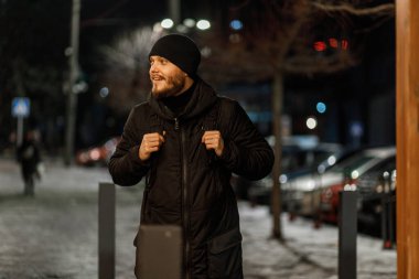 Sırt çantalı bir erkek turist kışın gece lambalarının arka planında yürür. Kayboldum..