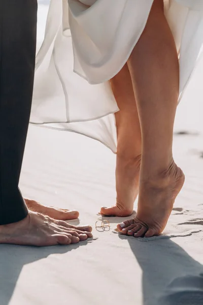 Close-up dari kaki seorang wanita dan seorang pria di atas pasir berlawanan satu sama lain Stok Foto Bebas Royalti