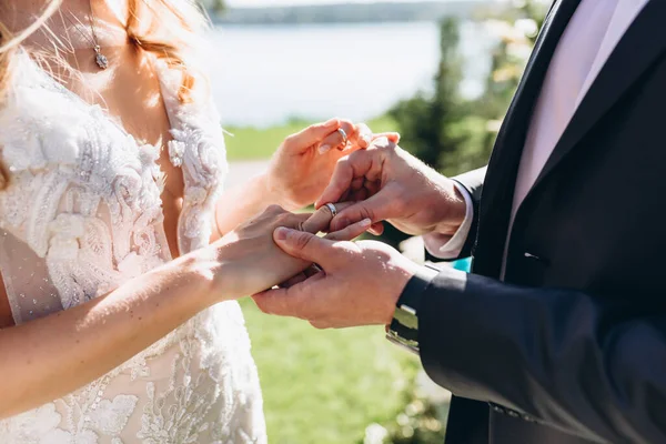Close-up do noivo coloca a aliança no dedo da noiva na cerimônia — Fotografia de Stock