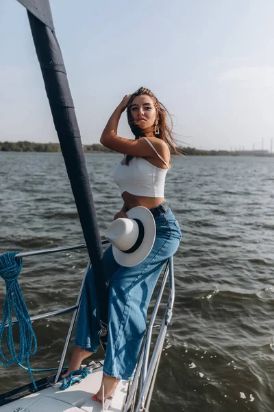 帽子を被った美しい若い女性がヨットの上に立っている — ストック写真
