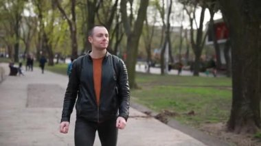 Şehir parkında akıllı saati olan yakışıklı bir genç. Bahar.