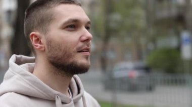 Genç adam şehir parkında yürürken kulaklık takıyor. turist