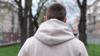 Genç adam şehir parkında yürürken kulaklık takıyor. turist