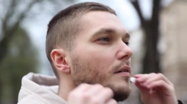 Genç adam şehir parkında yürürken kulaklık takıyor. turist