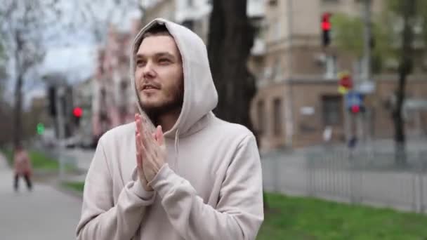 Jeune homme est froid et essayer de garder au chaud dans le parc de la ville frottant ses mains — Video