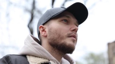 Genç adam şehir parkında yürürken kulaklık takıyor. turist