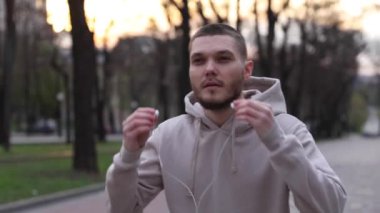 Genç adam şehir parkında yürürken kulaklık takıyor. turist