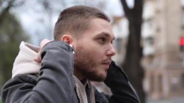 Genç adam bej kapüşonlu bir kapüşon giyer ve ellerini ovuşturur.