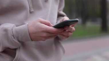 Şehir caddesinde elinde akıllı telefon tutan bir adamın yakın çekimi. Yüzü yok