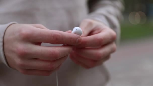 Close-up male hands holding white headphones in the city — Stock video