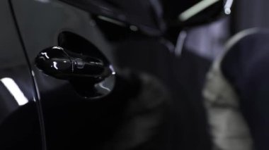 Professional black car wash, wipe the car after washing and tiling ceramics. Concepts: professional work, various detergents, cleaning to a shine.