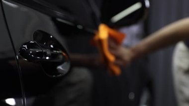 Professional black car wash, wipe the car after washing and tiling ceramics. Concepts: professional work, various detergents, cleaning to a shine.