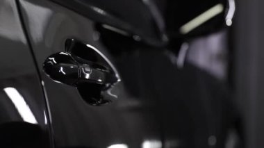 Araba servisi çalışanı bir araba detayına nano kaplama uyguluyor..