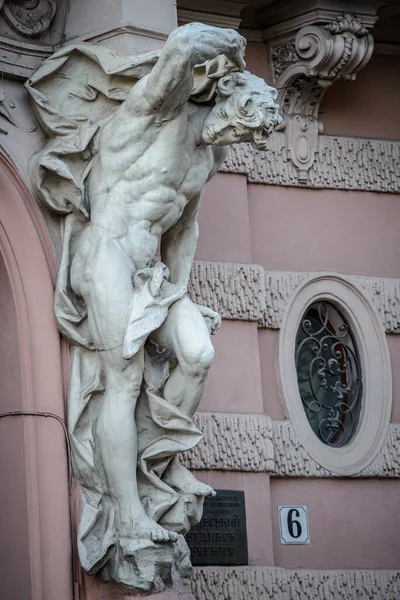 Bilim adamları Evi 'nin ana girişinde balkon destekleyen antik beyaz taş erkek heykeli. Eski soylu kumarhanenin binası. Lviv, Ukrayna. 