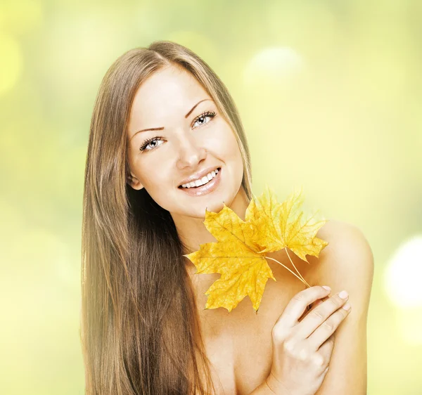 Mulher sorridente bonita, segurando folhas de outono — Fotografia de Stock