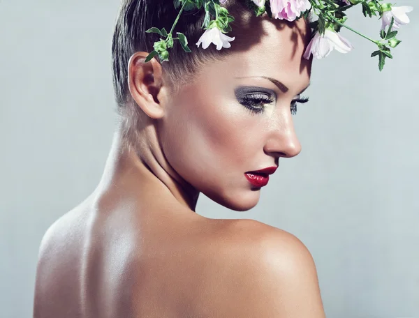 Belle jeune femme avec des fleurs sur la tête, maquillage glamour, mannequin — Photo