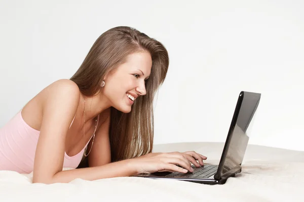 Menina feliz deitado na cama com laptop — Fotografia de Stock