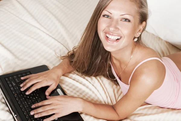 Menina feliz deitado na cama com laptop — Fotografia de Stock