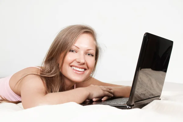 Menina feliz deitado na cama com laptop — Fotografia de Stock