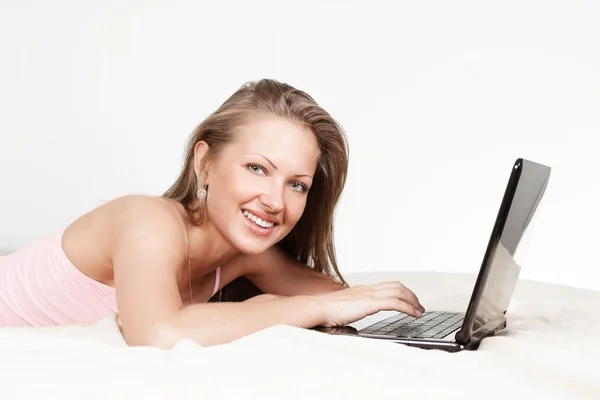 Glückliches Mädchen, das mit Laptop im Bett liegt — Stockfoto