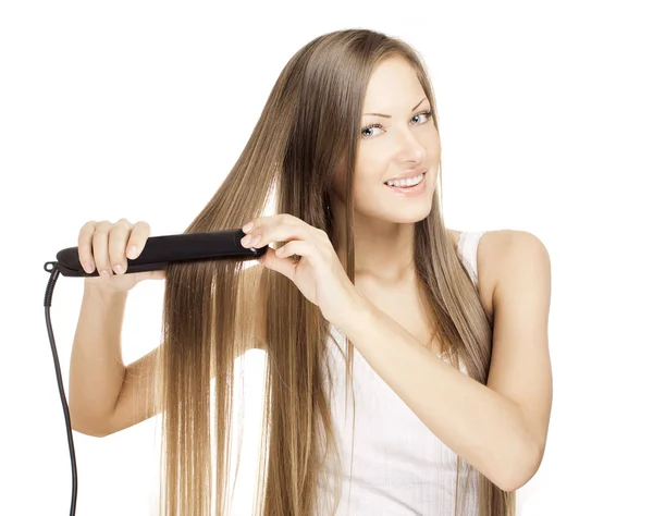 Beautiful young woman doing hairstyle with hair straightener — Stock Photo, Image