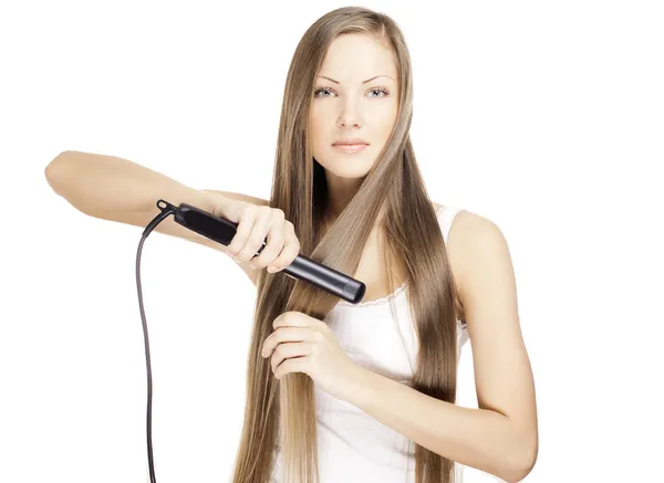 Beautiful young woman doing hairstyle with hair straightener — Stock Photo, Image