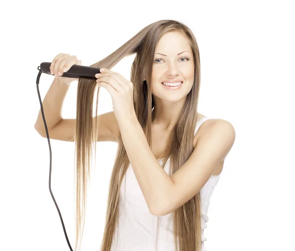 Όμορφη νεαρή γυναίκα που κάνει χτένισμα με το ίσιωμα των μαλλιών — Φωτογραφία Αρχείου