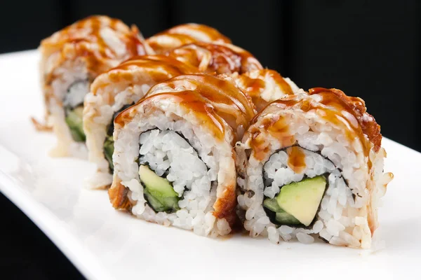 Close-up image of a japanese sushi roll on white plate over black background — Stock Photo, Image