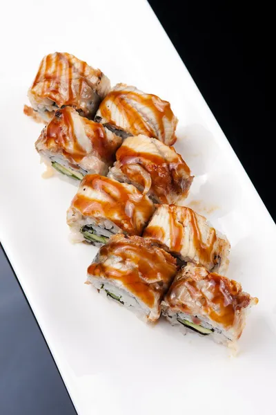 Bir Japon suşi roll ve siyah arka plan üzerine beyaz tabakta yakın çekim yansıma — Stok fotoğraf