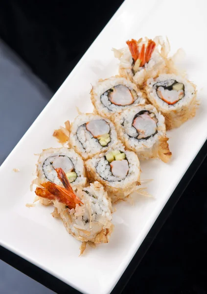 Close-up image of a japanese sushi roll on white plate over black background — Stock Photo, Image