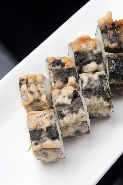 Bir Japon suşi roll ve siyah arka plan üzerine beyaz tabakta yakın çekim yansıma — Stok fotoğraf