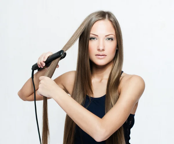 Vacker kvinna hoding hår järn — Stockfoto