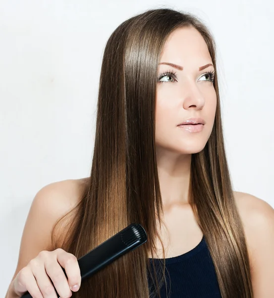 Красивая женщина собирает железо для волос — стоковое фото