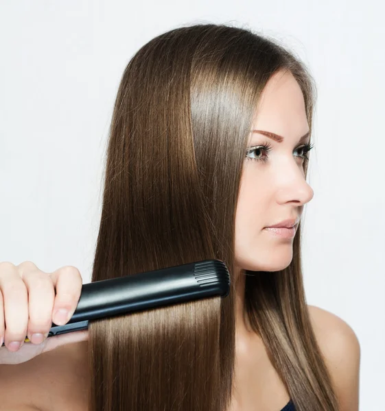 Beautiful woman hoding hair iron — Stock Photo, Image