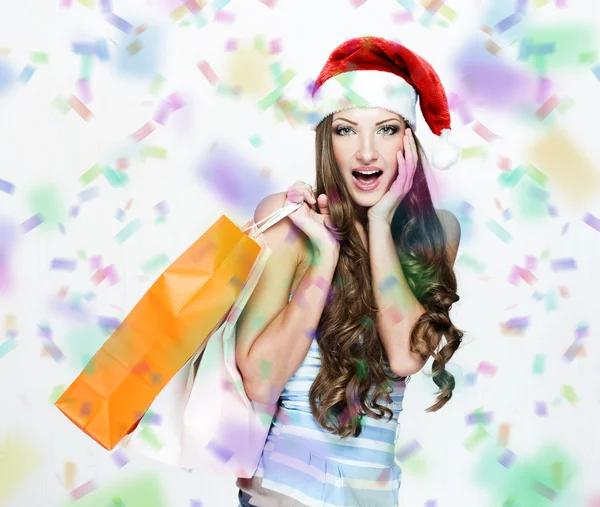 A portrait of a beautiful woman wearing Santa hat and holding shopping bags — Stock Photo, Image