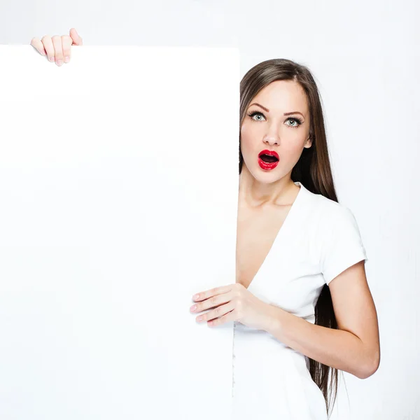 Mujer bonita sorprendida sosteniendo tablero blanco en blanco —  Fotos de Stock