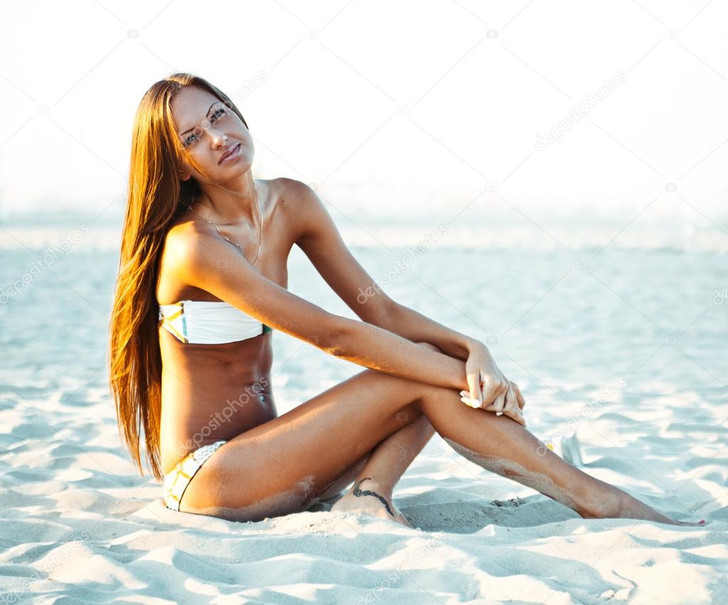 Smiling beautiful woman sunbathing on a beach