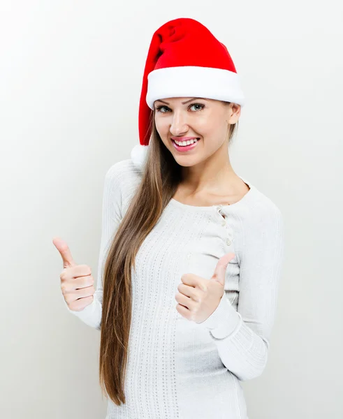 Flicka i jultomten hatt och visar tummen upp — Stockfoto