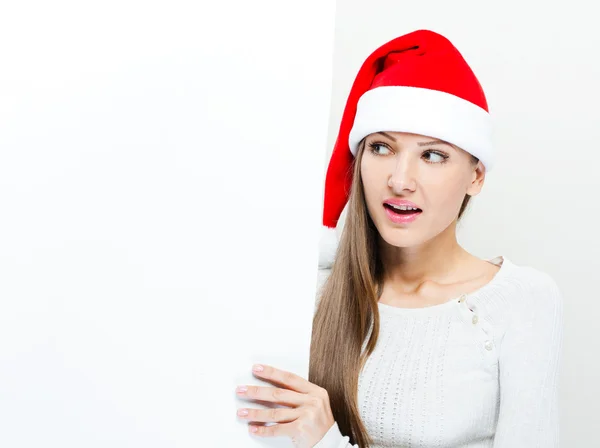 Девушка в шляпе Санта Клауса держит белую доску — стоковое фото