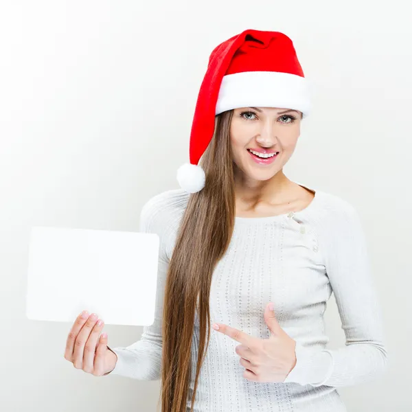 Menina em santa claus chapéu segurando uma placa branca — Fotografia de Stock