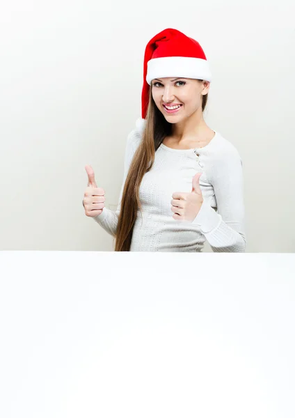 Девушка в шляпе Санта Клауса держит белую доску — стоковое фото