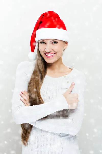 Menina em santa claus chapéu e mostra polegar para cima — Fotografia de Stock