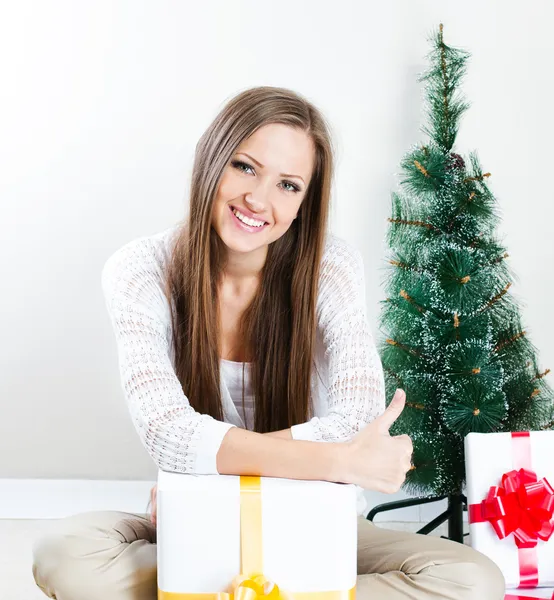 Женщина с рождественскими подарками, большой палец вверх — стоковое фото